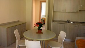 A small kitchen with a dining table, chairs, and cabinets. - Ferienwohnung fur 4 Personen in Imperia (Imperia)
