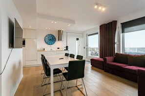 Un salon moderne avec un coin repas, une grande fenêtre avec des rideaux et une vue sur la ville.