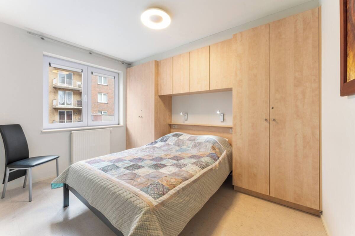 Une chambre à coucher avec un lit, une chaise, une fenêtre et des armoires en bois.