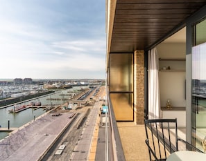 Un balcon donnant sur un port de plaisance et une zone industrielle.