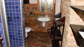 A bathroom with a tiled wall, a sink, a mirror, a toilet, and a wooden chair. - Farmhouse in Modigliana With Scenic Views (Modigliana)