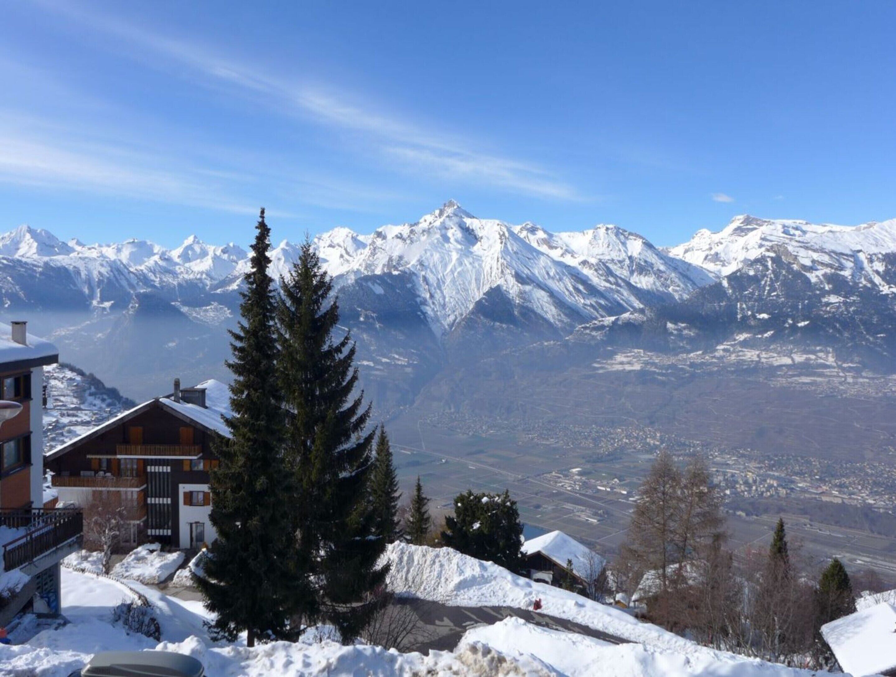Una cabaña de montaña con vistas a picos nevados.