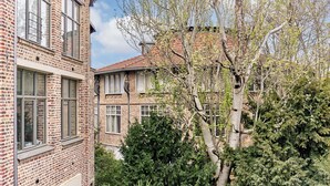 A multi-story brick building with large windows and a tree in the foreground. - Cosy Apartment Parc des Expositions/eiffel Tower (Paris)