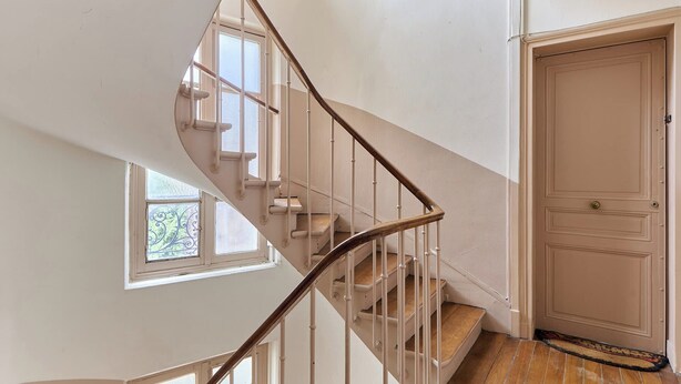 A spiral staircase with a wooden handrail, a door with a brass handle, and a window with decorative glass. - Cosy Apartment Parc des Expositions/eiffel Tower (Paris)