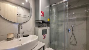 Un baño moderno con lavamanos, espejo y cabina de ducha de vidrio.