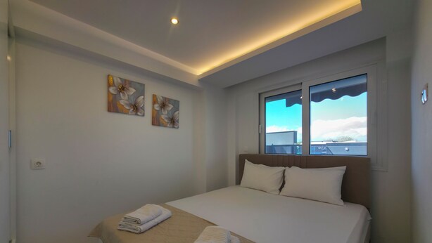 Un dormitorio con una cama, dos almohadas, una ventana y obras de arte en la pared.