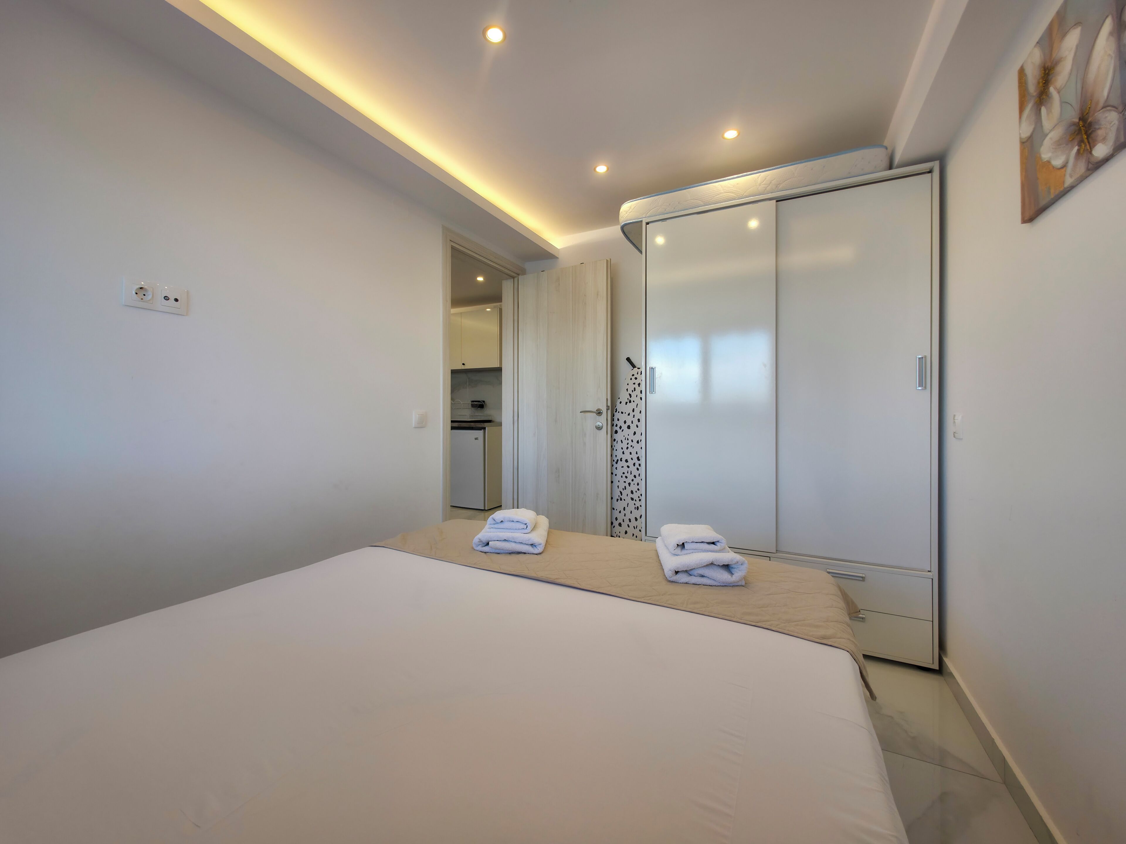 Ein Schlafzimmer mit einem Bett, einem Kleiderschrank und einem durch eine offene Tür einsehbarer Badezimmer.