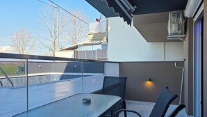 Un patio techado al aire libre con una mesa, sillas, barandilla y vistas del entorno.