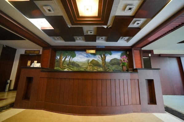A reception desk with a mural, a sign indicating the reception area, and a modern ceiling design.