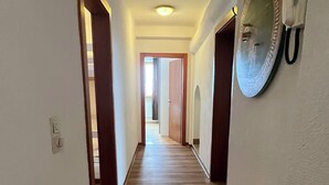 A hallway with wooden flooring, white walls, and a door leading to another room. - Apartment Saalfelden 23 (Saalfelden am Steinernen Meer)