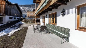 A building with a balcony, outdoor seating, and a view of a snowy landscape. - Apartment Saalfelden 23 (Saalfelden am Steinernen Meer)