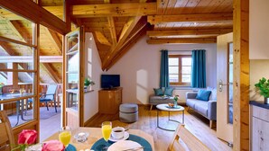 A cozy room with a dining table set for breakfast, a sofa, and a TV in the background. - Vacation apartment Sonnenblume, up to 2 persons, top floor, 50 sqm (Waging am See)
