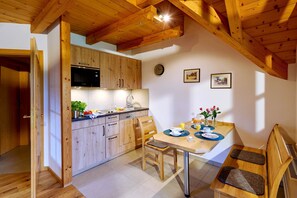 Eine Küche mit Holzausstattung, einer Mikrowelle und einem Essbereich mit Tisch, Stühlen und einer Bank.