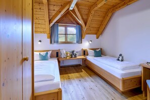 A room with two wooden beds, a window with curtains, and a wooden ceiling. - Vacation apartment Schlüsselblume, up to 4 persons, attic, 65 sqm (Waging am See)