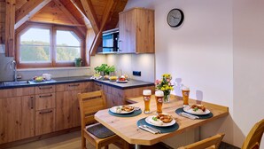 A cozy kitchen with wooden cabinets, a dining table set for two, and a clock on the wall. - Vacation apartment Schlüsselblume, up to 4 persons, attic, 65 sqm (Waging am See)