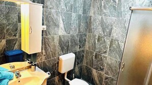 A bathroom with a marble wall, a sink with a mirror, a toilet, and a cabinet. - Tremendous 2-bedroom Apartment with AC in tranquil Vodice (Vodice)