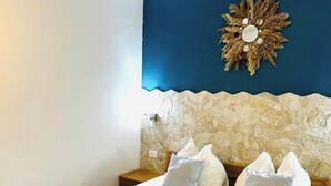A hotel room with a bed, pillows, a wall-mounted decor piece, and a stone-like textured wall. - Tremendous 2-bedroom Apartment with AC in tranquil Vodice (Vodice)