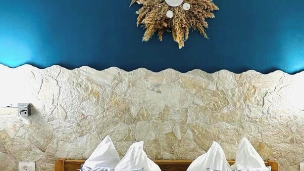 A hotel room with a bed, white pillows, a decorative wall mirror, and a textured stone wall. - Tremendous 2-bedroom Apartment with AC in tranquil Vodice (Vodice)