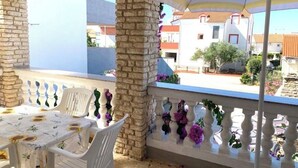 A balcony with white chairs, a table with a floral tablecloth, and a stone pillar. - Tremendous 2-bedroom Apartment with AC in tranquil Vodice (Vodice)