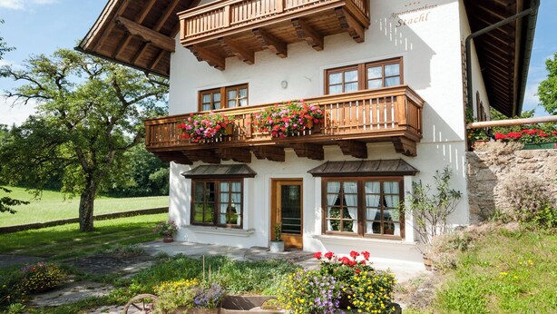 Un edificio de dos pisos con un balcón de madera y macetas con flores.