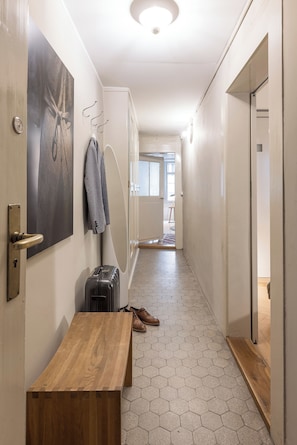 A hallway with a wooden bench, a coat rack, a suitcase, and a door leading to another room. - Bijou in the middle of the old town of Bern (Bern)