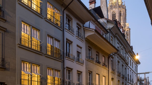 Eine Reihe historischer Gebäude mit aufwendigen Balkonen und einem Kirchturm im Hintergrund.