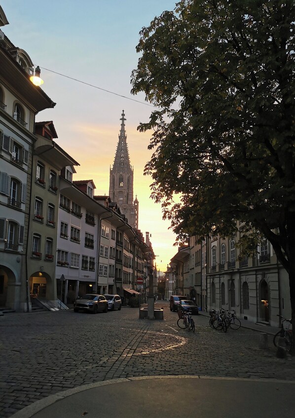 A cobblestone street lined with historic buildings, a church spire in the background, and bicycles parked along the sidewalk. - Bijou in the middle of the old town of Bern (Bern)