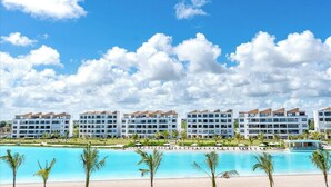 Ein Hotel mit mehreren Gebäuden, einem Schwimmbad und einer Strandanlage.