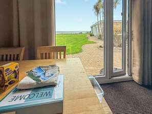 A hotel room with a view of the beach, a wooden table with a welcome mat, and a mini egg carton on the table. - No 3 Hickling Chalet - UK51728 (California, near Great Yarmouth)