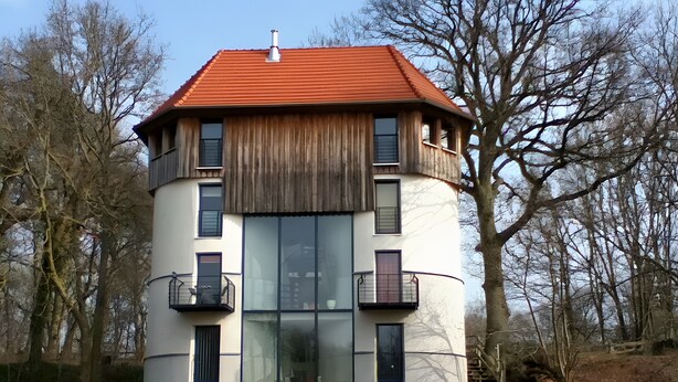 Un immeuble à plusieurs étages, doté d’un toit rouge, de balcons et de grandes fenêtres.