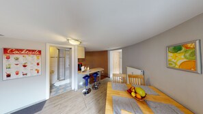 Eine moderne Küche mit Barbereich, einem Esstisch mit Obstkorb und einer 'Cocktails'-Speisekarte an der Wand.