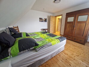 A bedroom with a bed, wooden wardrobe, and a small table. - Spacious vacation home with far-reaching views (Kall)