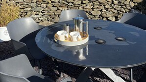 A round table with chairs, a metal pot, and cups, set against a stone wall and a grassy field. - The Old School Glasfryn | Dog Friendly | Betws y Coed 15 min | Ideal for Snowdon (Glasfryn)