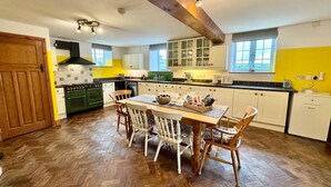 A kitchen with a dining table, chairs, and a wooden ceiling beam. - The Old School Glasfryn | Dog Friendly | Betws y Coed 15 min | Ideal for Snowdon (Glasfryn)