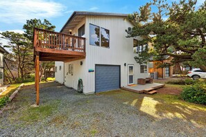 A modern two-story house with a balcony, a garage, and a driveway. - Movie Room + Fire Pit + Deck with Views + Walk to the Beach | Magic Tree House (Manzanita)