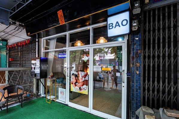 En BAO-restaurang med en entré som har en glasdörr, ett litet utomhusområde med sittplatser och stolar samt en väl synlig skylt.