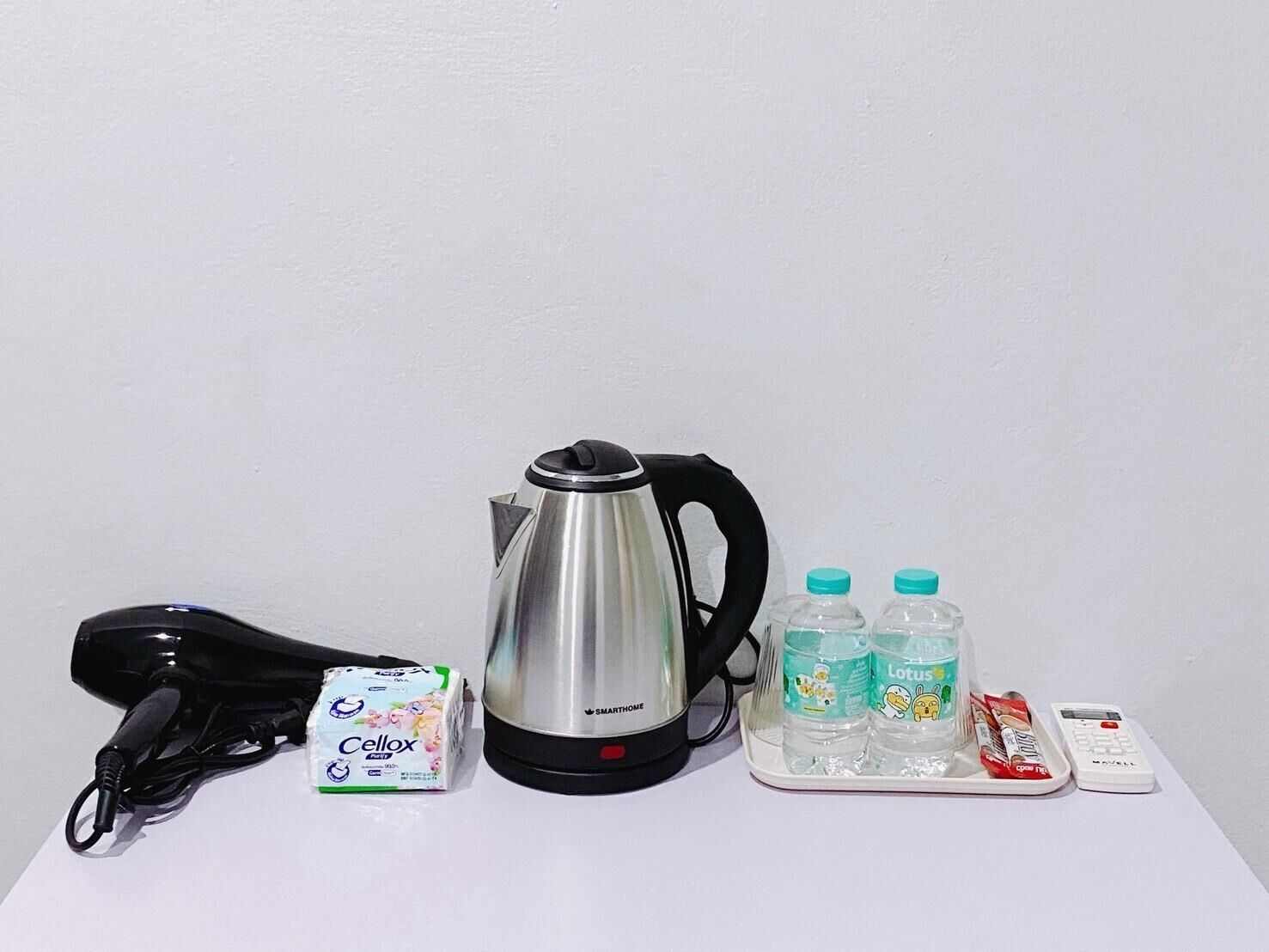 A kettle, a hairdryer, a carton of milk, two water bottles, and a remote control on a white surface.
