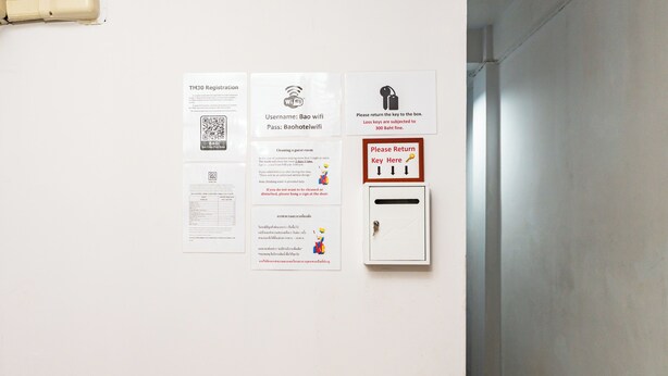 Seinällä on useita informatiivisia julisteita, joihin sisältyy muun muassa QR-koodi, Wi-Fi-tunnus, siivohjeet ja opaste avainten palautuspisteeseen.