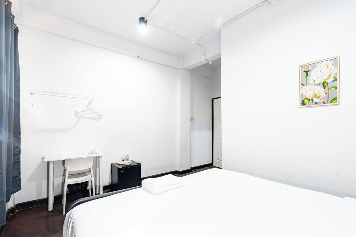 Ein Hotelzimmer mit Bett, Schreibtisch, Stuhl, einem kleinen Tisch mit Pflegeprodukten und einem Bild an der Wand.