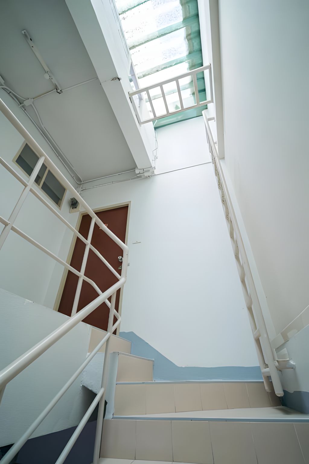 Una escalera con barandilla y una puerta al final.