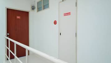 A staircase with a white handrail, a wooden door labeled '101', and a fire alarm on the wall.