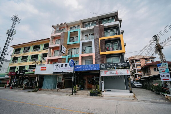 A multi-story building with various shops on the ground floor, including a hair salon. - Oh My Nap Bangsaen (Chonburi)