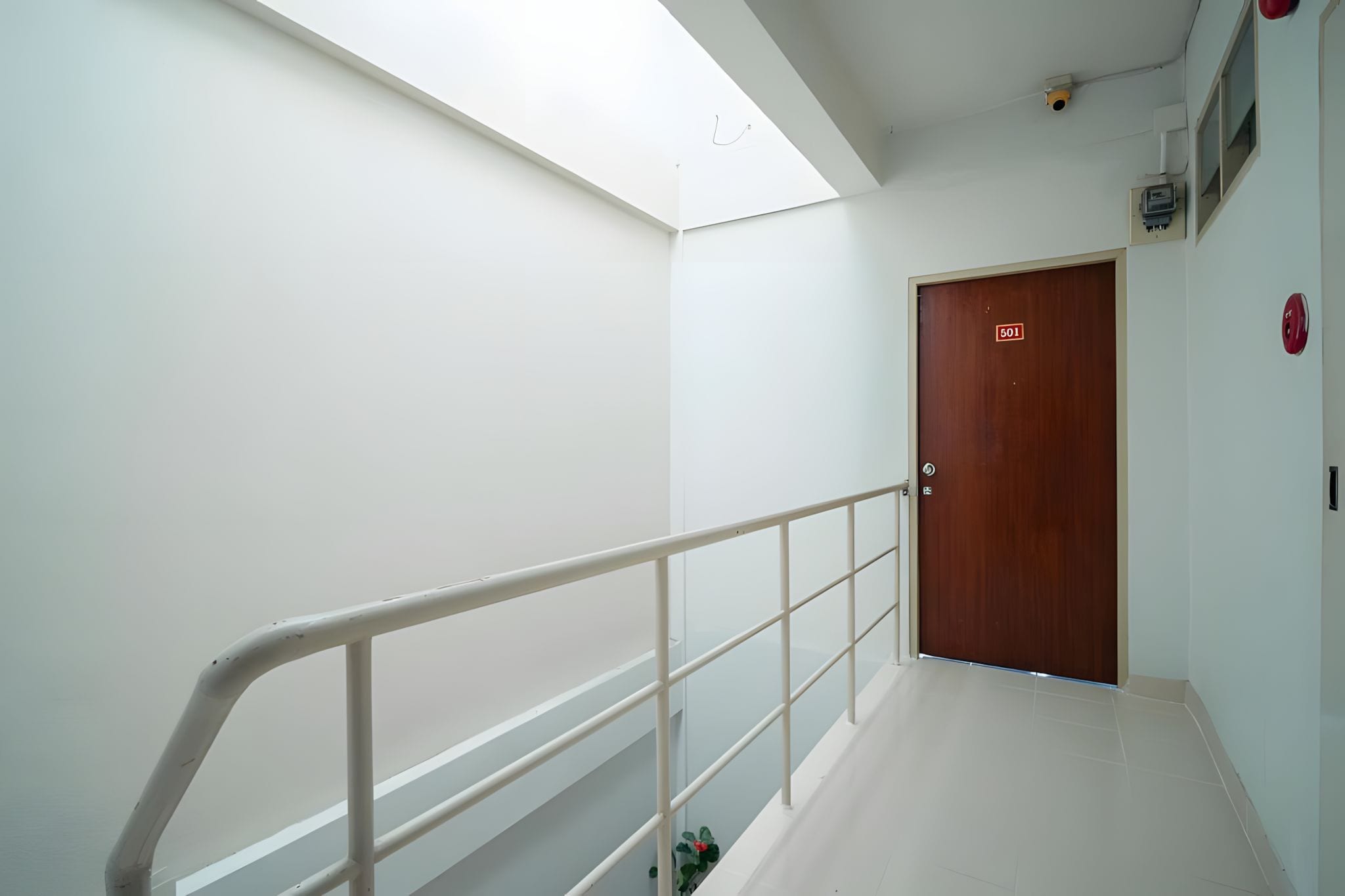 Corredor limpo e moderno com porta de madeira com a inscrição '501' e corrimão branco.