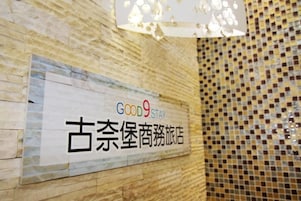 Een muur met een bord waarop 'GOOD9STAY' en '古奈堡商旅酒店' in het Engels en een andere taal staat.
