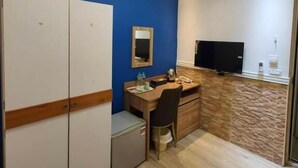A hotel room with a desk, wardrobe, and a television. - Good 9 Stay Inn (Taipei)