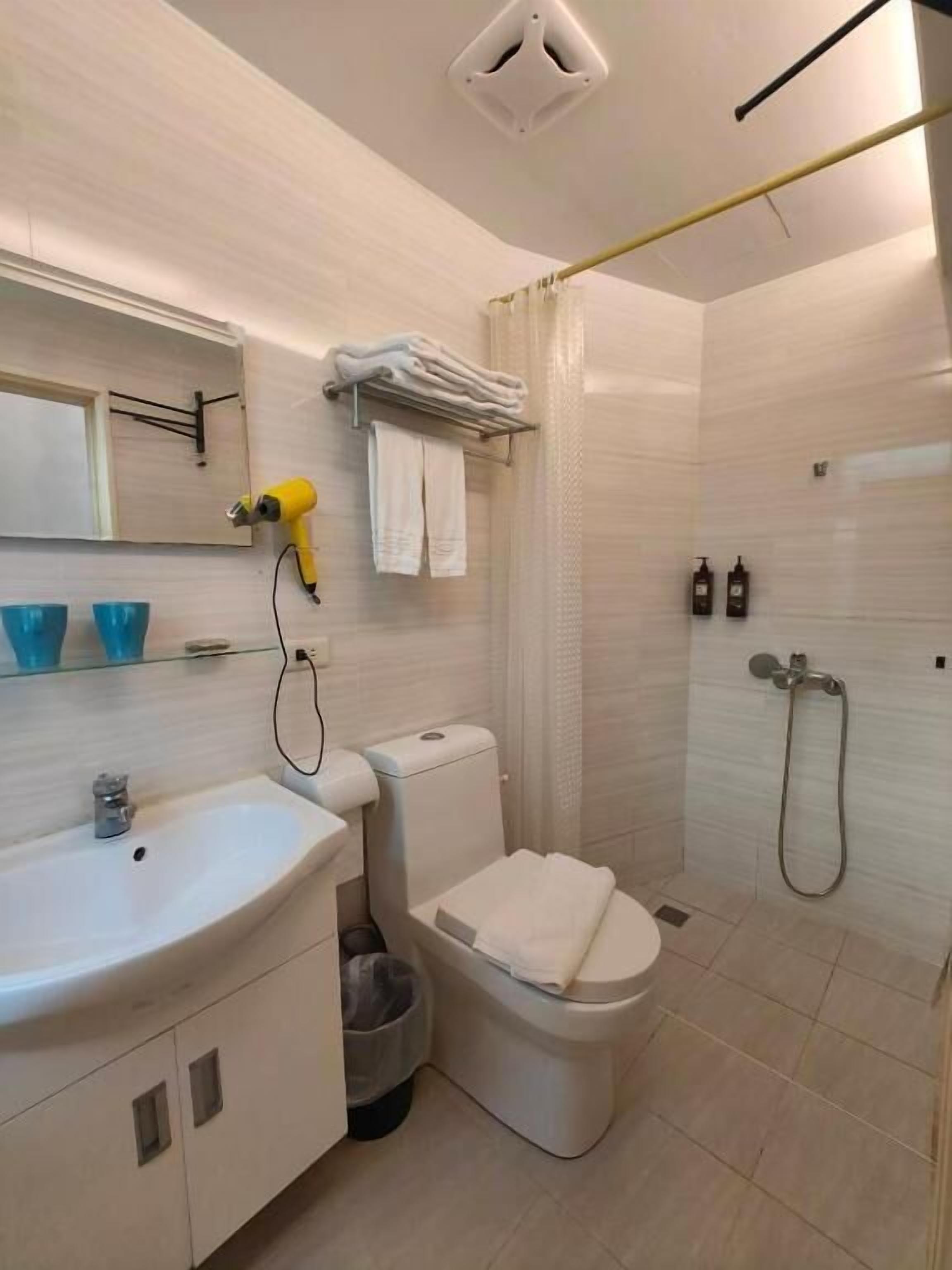Un bany amb rentatge, vàter, dutxa i paraigua per tovallons.