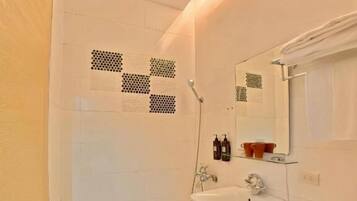 A bathroom with a shower, toilet, sink, and a mirror.