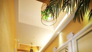 A hallway with a door marked '570', a ceiling light fixture, and a plant. - Good 9 Stay Inn (Taipei)
