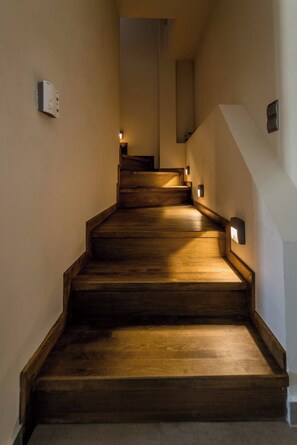 A wooden staircase with wall-mounted lights, leading to an upper floor. - Irodotou Two Storey Apartment Magic View (Kefalonia)