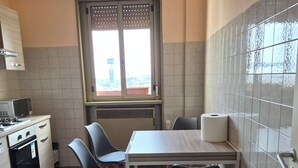 A compact kitchen with a dining table, two chairs, a microwave, a stove, and a window with a view. - Venice Nice apartment (Venezia)
